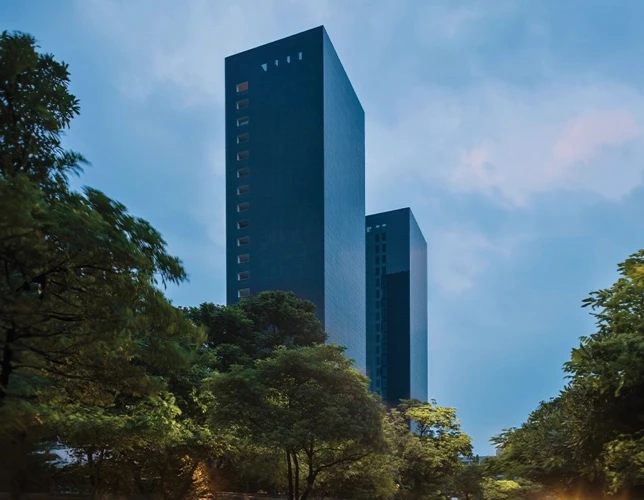 Exterior view of the two dark glass Trump Towers Pune buildings above landscaped grounds.