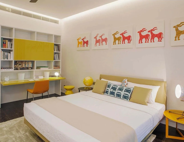 Bedroom interior with built-in desk and yellow accents shown for Trump Towers Pune.